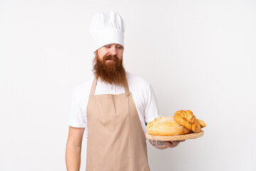 Redhead man in chef uniform. Male baker holding a table with several breads with sad expression