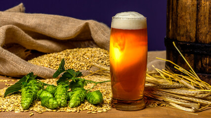 Beer. Still life with Vintage beer barrel and glass light beer. Fresh amber beer concept. Green hop...