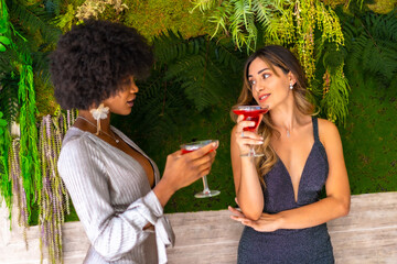 Two friends in gala dresses having a cocktail at a party in a hotel, lifestyle. Glamor lifestyle, exclusive party