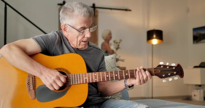 elderly old caucasian couple having fun playing guitar at home,retired people enjoy time at home dancing and playing musical instrument