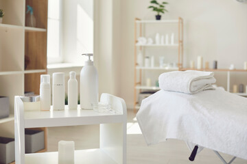 Spa room or beauty salon with set of organic skincare products and empty bed with fresh towels