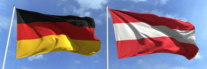 Flags of Germany and Austria on flagpoles. 3d rendering