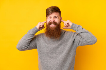 Redhead man with long beard over isolated yellow background frustrated and covering ears