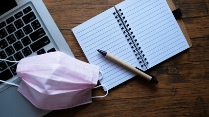 face mask on laptop, covid-19 concept and new normal.