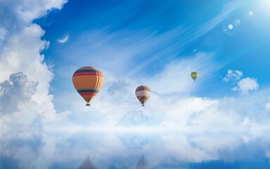 Hot air balloons rising above serene sea, light from heaven, white clouds reflected in water.