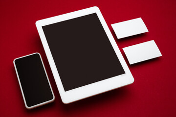 Devices with blank screens floating above red background. Phone, tablet, card. Office styled, modern mockup for advertising, image or text. Blank white copyspace for design, business and finance