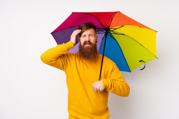 Redhead man with long beard holding an umbrella over isolated white background unhappy and frustrated with something. Negative facial expression