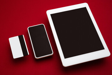 Devices with blank screens floating above red background. Phone, tablet, card. Office styled, modern mockup for advertising, image or text. Blank white copyspace for design, business and finance