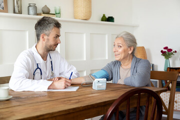 Regular checkup of grandmother using medical digital tonometer at home