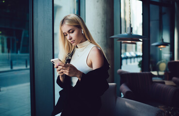 Concentrated woman using smartphone and listening to music in cafe