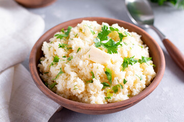 Couscous in a bowl with butter on a light table