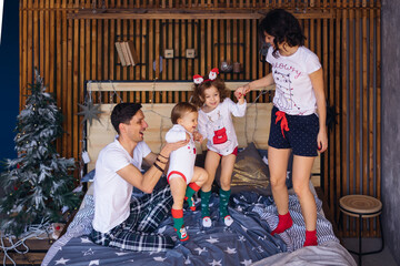 parents and children holding hands and having fun on the bed. Ch