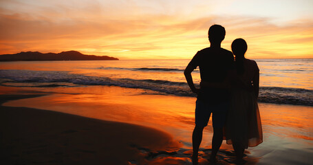 couple stand on sunset beach