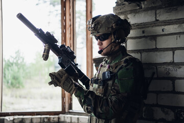 Brutal military man is sitting and cleaning and preparing his gun to the battle.