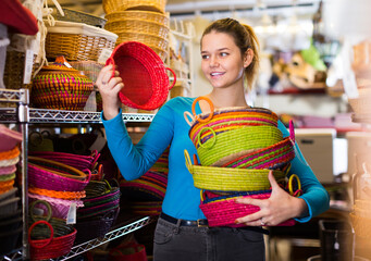 .young woman customer choosing multicolor wicker basket in decor items store