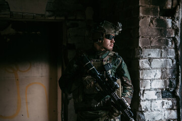 A thoughtful soldier, resting from a military operation while it is raining outside.