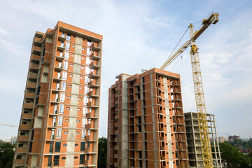 High-rise residential apartment buildings and tower crane under development on construction site. Real estate development.