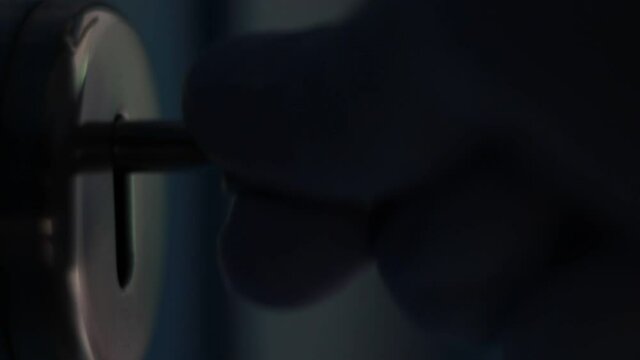 Fingers manipulate with key in a key lock. Close up, macro.