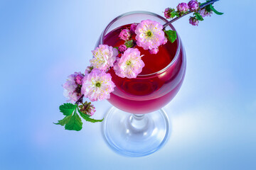 Obraz na płótnie Canvas Sprig of spring pink sakura flower on a glass of red wine