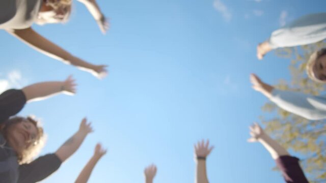 Bottom view of young diverse people putting their hands together outdoors.