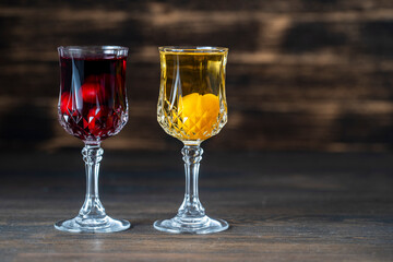 Homemade tincture of red cherry and yellow cherry plum in a wine crystal glasses on wooden background, Ukraine