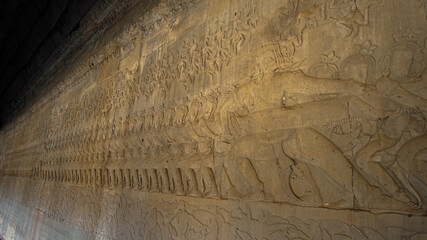 Ancient Khmer bas relief carving showing a row of Asura, giants, pulling on the snake Vasuki. Legend of the churning of the Ocean of Milk, Angkor Wat temple, Cambodia.