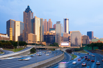 Obraz premium Skyline of Atlanta at sunset with traffic in the freeway.