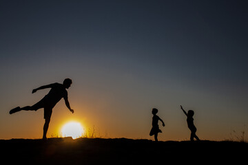 Fun, symbolic abstract photo at sunset-the sun-a ball with which a father and children play football