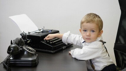 Loving blond hair and blue eyes child typing at vintage typewriter