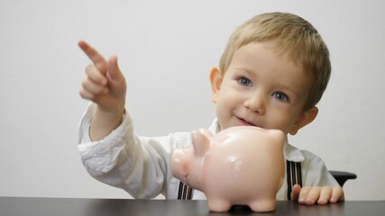 Confident little child put money and raise up his piggy bank proud of his saving plan