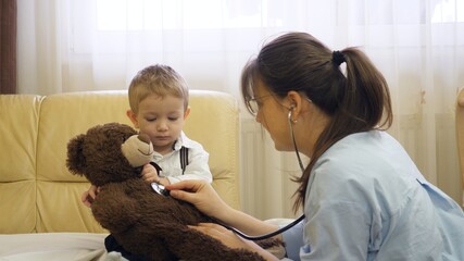 Female doctor consult little baby child and teddy bear toy, friendly examination