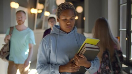 Portrait of sad african female student walking through university corridor - Powered by Adobe