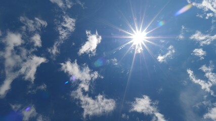 Few white scattered Cirrus clouds on deep blue sky against bright sun light star shape rays,...