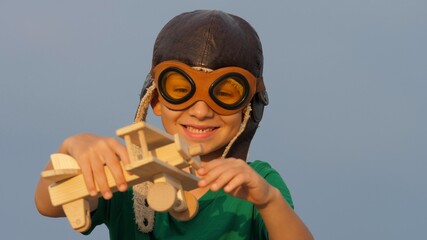 Little boy with pilot cap and eyeglasses plays with wooden plane toy and smile © MEDIAIMAG