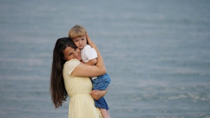 Mother holding little child at seaside, soft parent caress, strong bonding