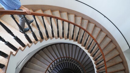 Man going down the interior spiral stairs of luxury modern building