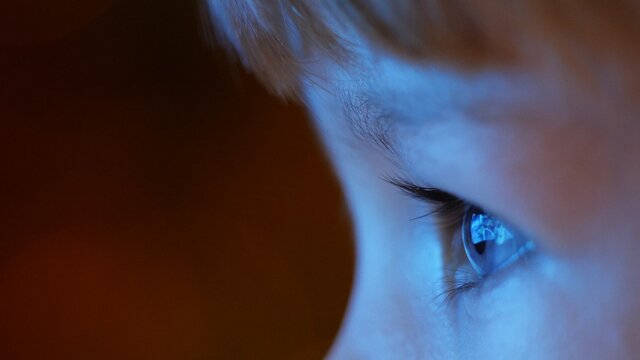 Close of blue eyes child focus on tv, late night modern education, conceptual