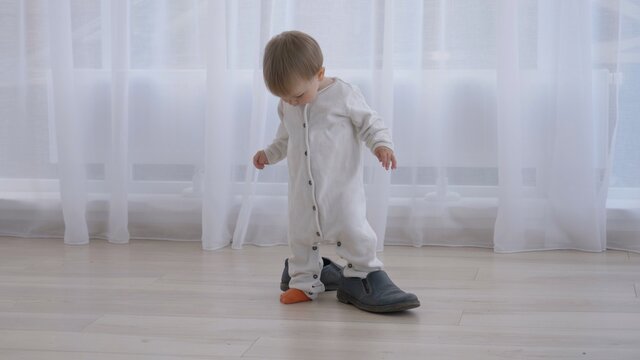 Little baby trying to wear daddy's big shoes