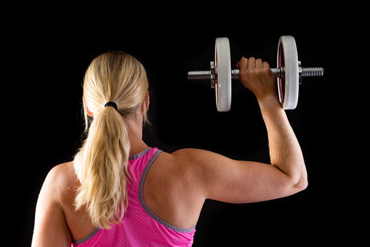 Fitness woman wearing pink top lifting dumbbell isolated on black background