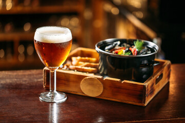 Glass of golden beer with mussels snack bucket