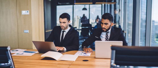 Diverse colleagues surfing Internet on laptops in contemporary workplace