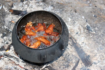 Chicken wings deep-fried in a pot on a fire