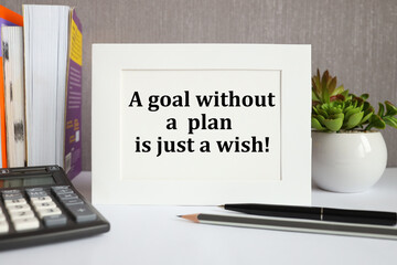 a goal without a plan is just a wish. on white paper in a LIGHT frame, on a gray background, near books and a calculator