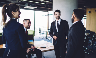 Experienced crew of diverse executive managers smiling during business conversation for discussing together briefing, happy male and female partners enjoying friendly environment in corporate office