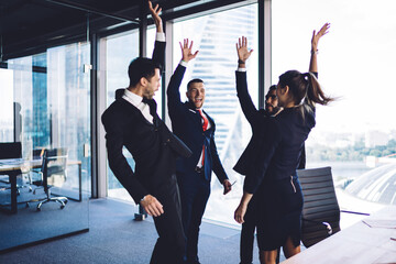 Multicultural corporate partners in formal wear enjoying synergy association during working day for brainstorming collaboration, successful men and woman celebrating approved business project