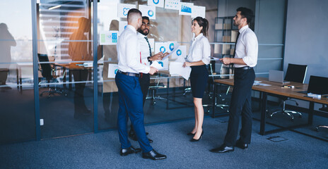 Diverse group of successful colleagues analyzing financial information search exchange solutions during business brainstorming in office, collaboration process for discussing infographics revenue