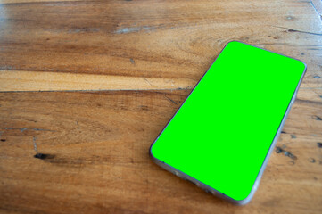 Green screen smartphone on wooden table