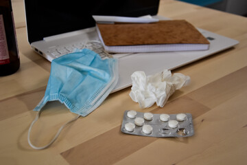 Being sick working from home. Protection mask, pills and napkin to prevent the spread of virus. Covid-19