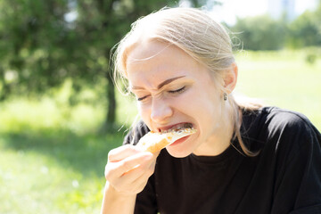 Beautiful girl eating trying tasting pizza outdoor in park