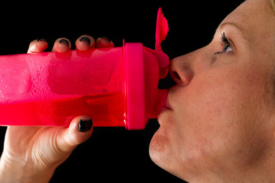 Close up on woman drinking energy drink from pink bottle